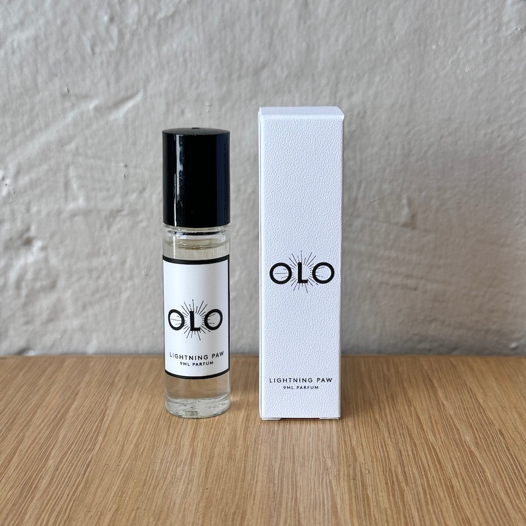OLO perfume bottle and packaging on a wooden surface with a gray background