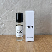 OLO perfume bottle and packaging on a wooden surface with a gray background