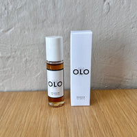 OLO perfume bottle and packaging on a wooden surface with a gray background