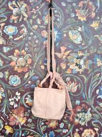 Pink canvas handbag with a strap on a floral-patterned background
