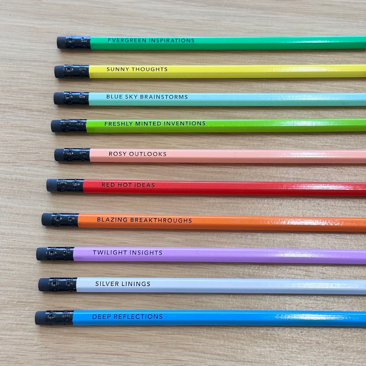 Row of colorful pencils with motivational phrases on a wooden surface