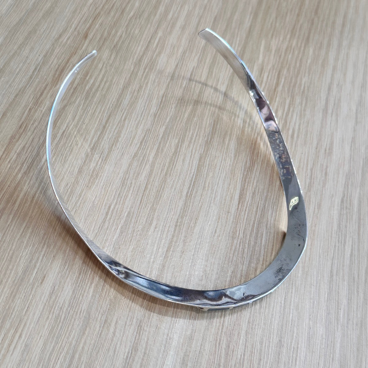 Backside of a silver necklace on a wooden surface