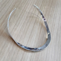 Backside of a silver necklace on a wooden surface
