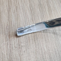 end of a silver necklace with '925' engraving on a wooden surface