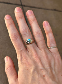 Hand wearing two rings on a neutral background
