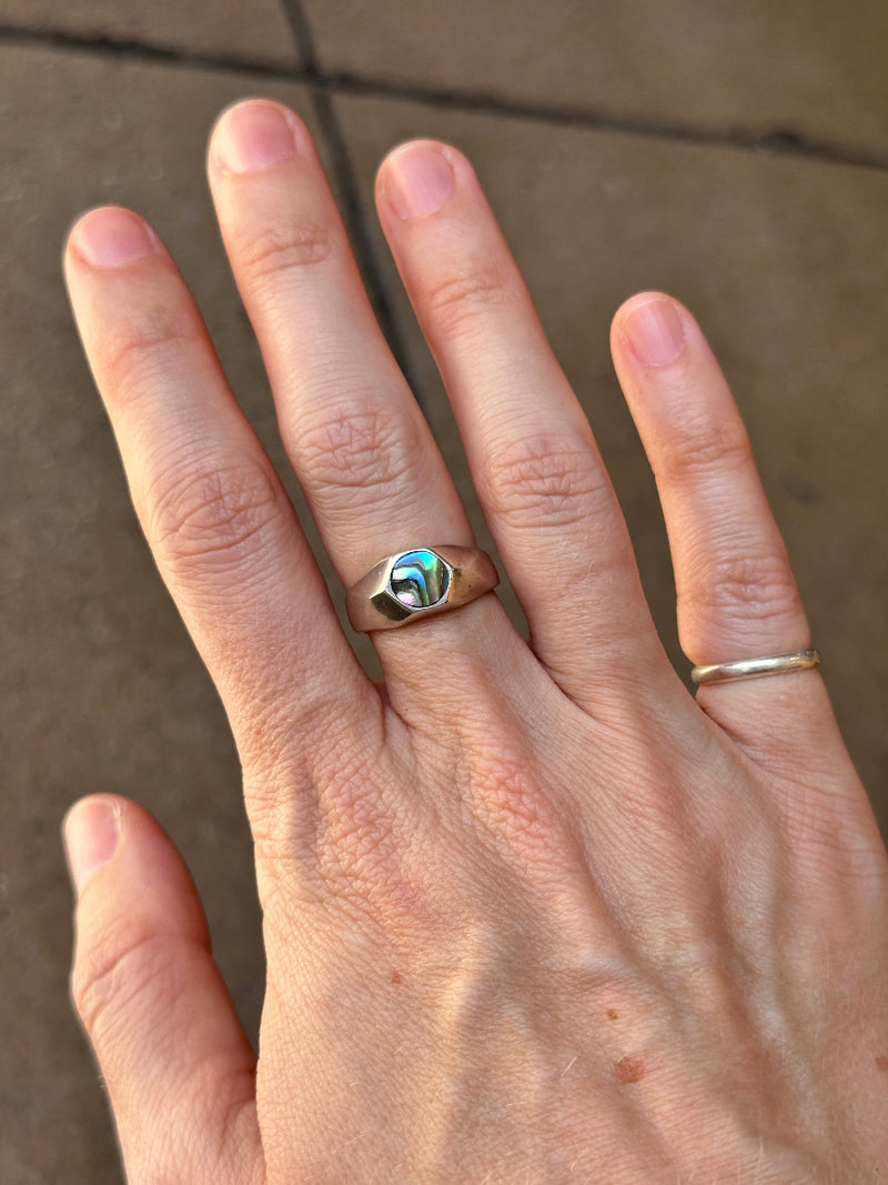 Hand wearing two rings on a neutral background
