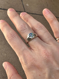 Close-up of a hand wearing a ring on a concrete surface