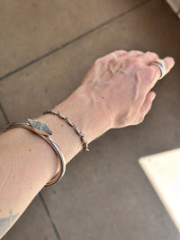 Hand wearing multiple bracelets on a neutral background