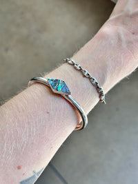 Silver bracelet with abalone inlay on a wrist against a neutral background