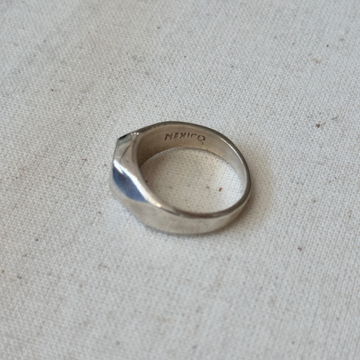 Silver ring with 'Mexico' engraving on a light fabric background