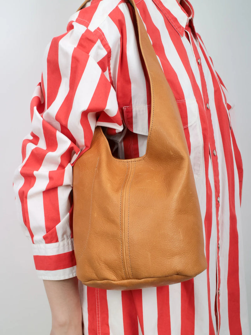 Person wearing a red and white striped shirt with a tan leather bag over their shoulder