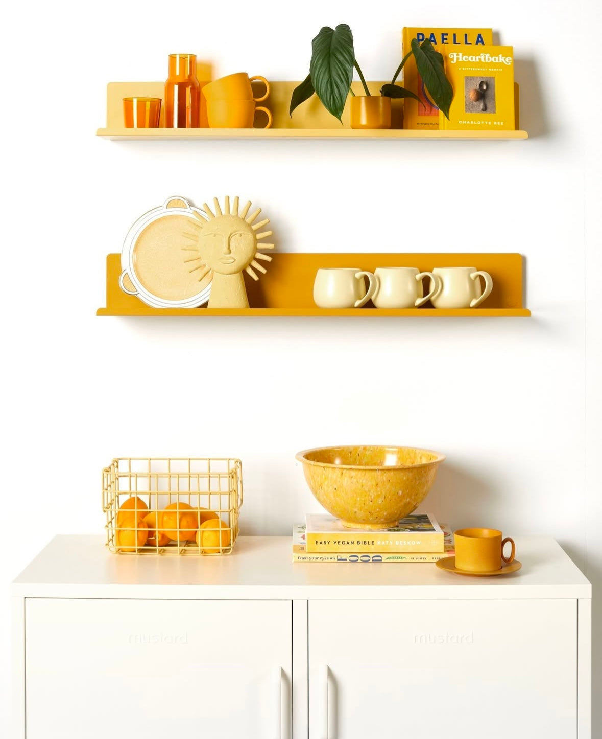 Kitchenware on yellow shelves against a white wall