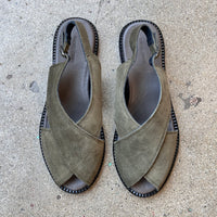 Pair of green suede sandals on a concrete surface