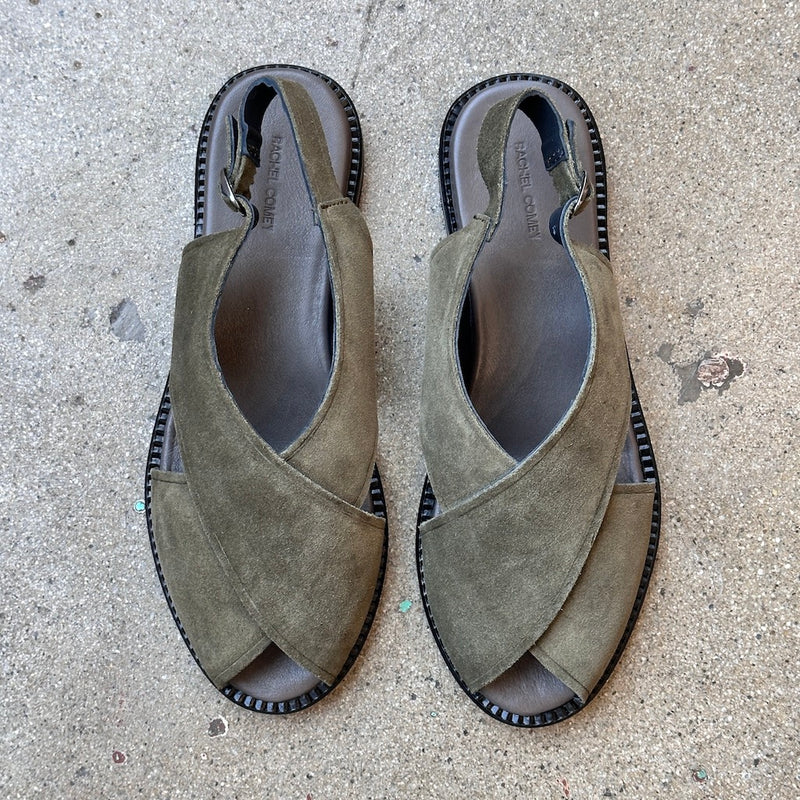 Pair of green suede sandals on a concrete surface