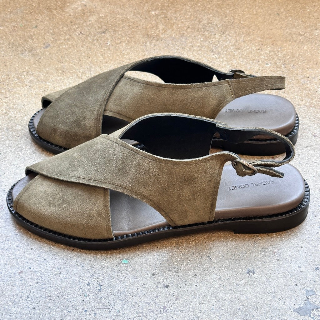 Side of green suede sandals on a concrete surface