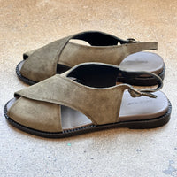 Side of green suede sandals on a concrete surface