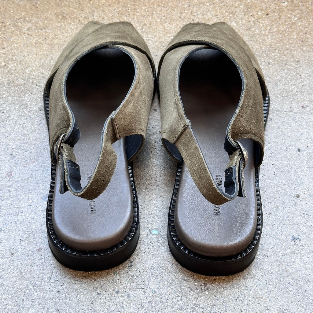 Back of green suede sandals on a concrete surface
