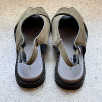 Back of green suede sandals on a concrete surface