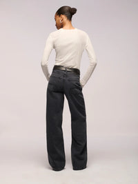 Person wearing a white long-sleeve shirt and black jeans on a light gray background