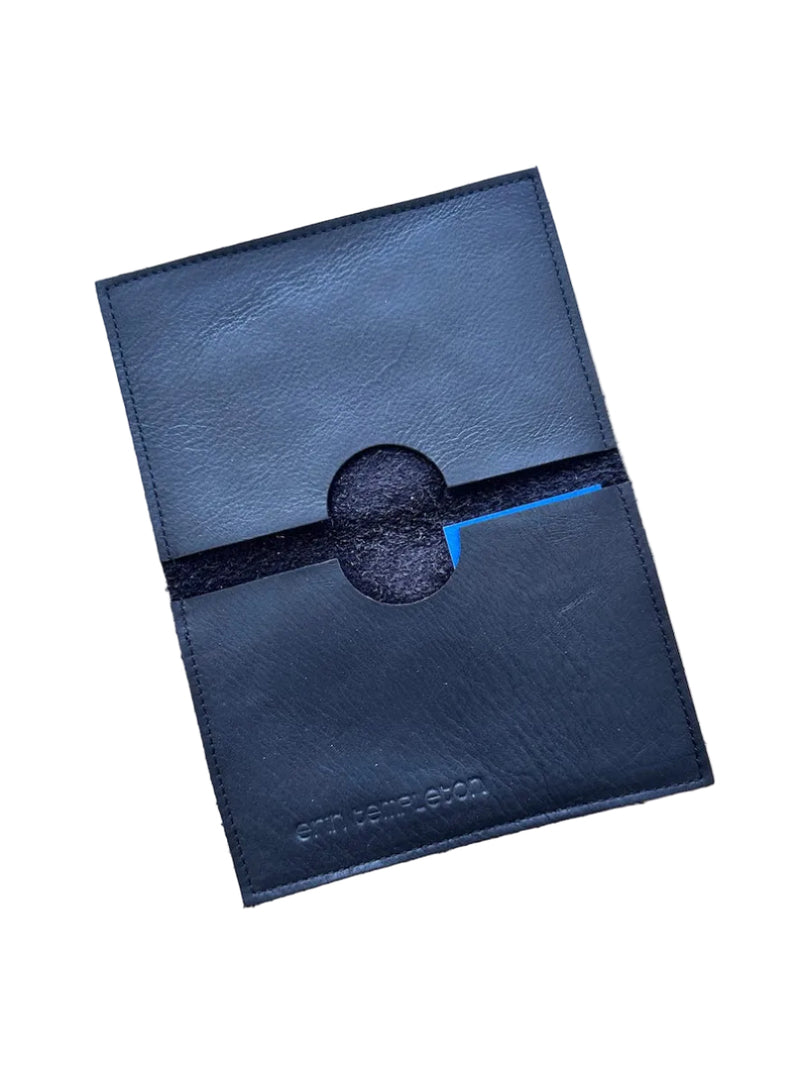 A black leather passport case with a circular cutout in the center pockets, shown on a white background.