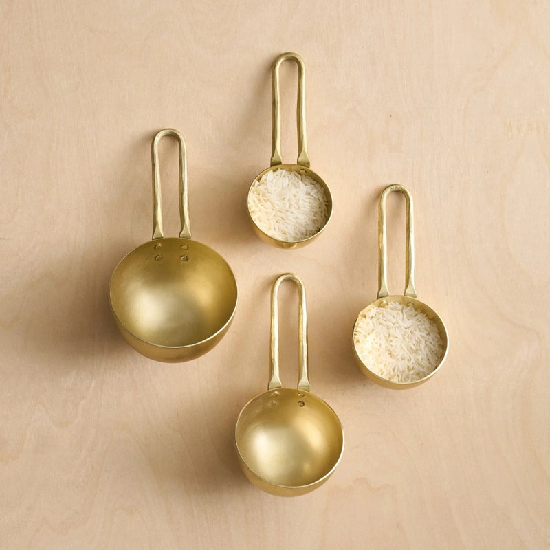Set of four round brass measuring cups on a wooden surface