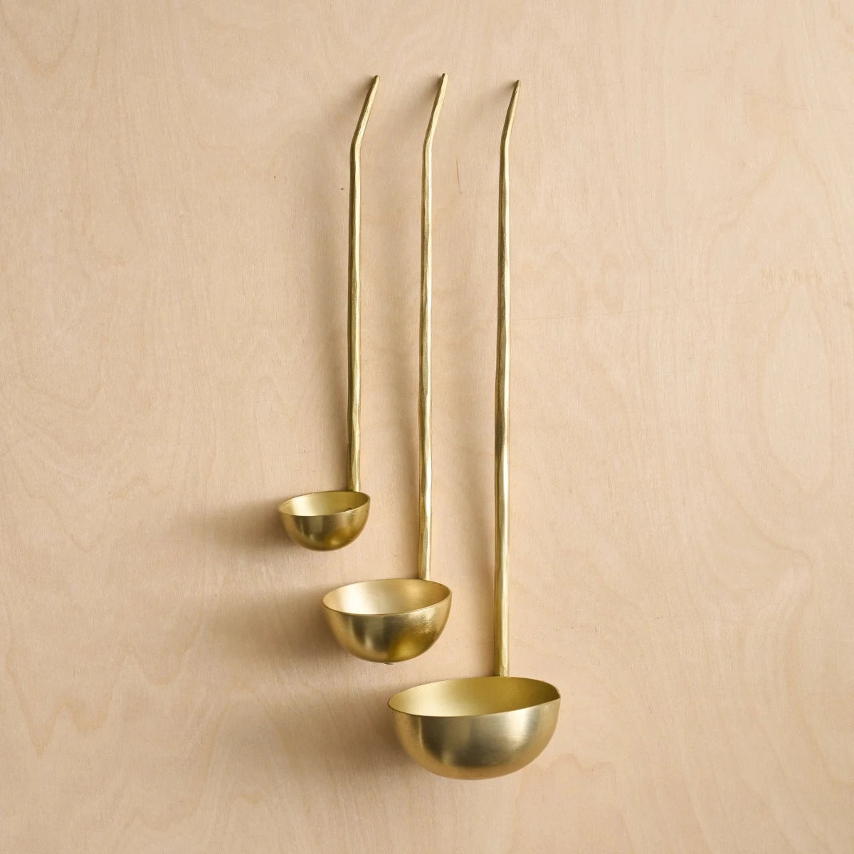 Set of three brass ladles on a wooden surface