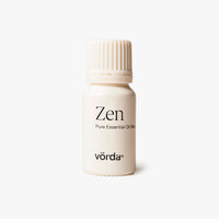 Off-white bottle with ribbed cap labeled 'Zen Pure Essential Oil Blend' and 'vörda' on a light grey background
