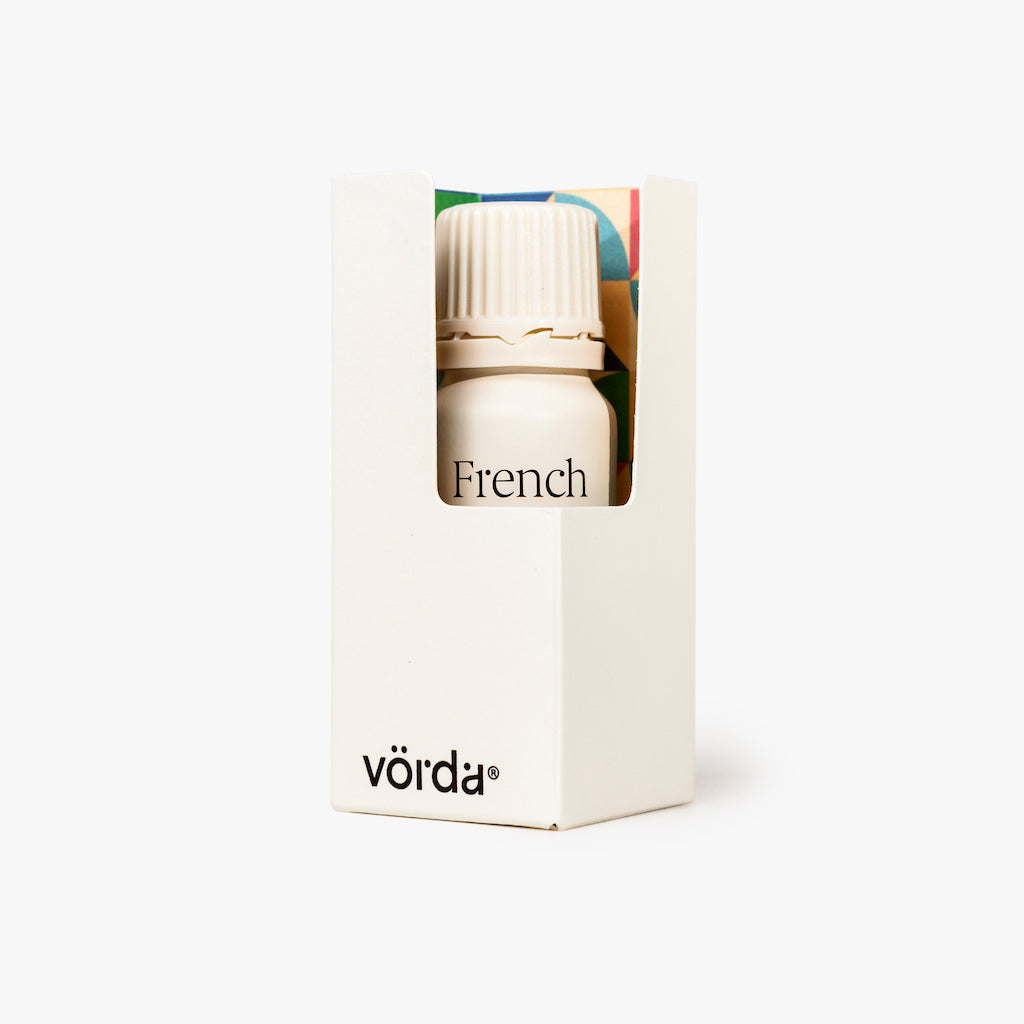 A small white bottle with a ribbed cap inside a white box, with the word 'French' printed on the front and the brand name 'vörda' near the bottom. The box has a small colorful window showing part of the bottle.