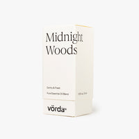 A minimalist white product box for Vörda Midnight Woods essential oil blend, featuring black text and shown on a clean, light off-white background.