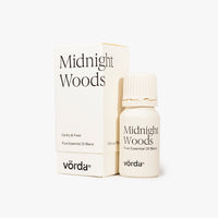 A small white bottle of Vörda Midnight Woods pure essential oil blend stands in front of its matching white box on a clean white background.