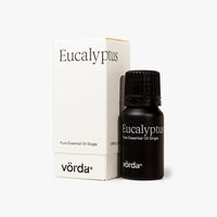 Vörda Eucalyptus pure essential oil single bottle in black next to its white packaging box on a light gray background.