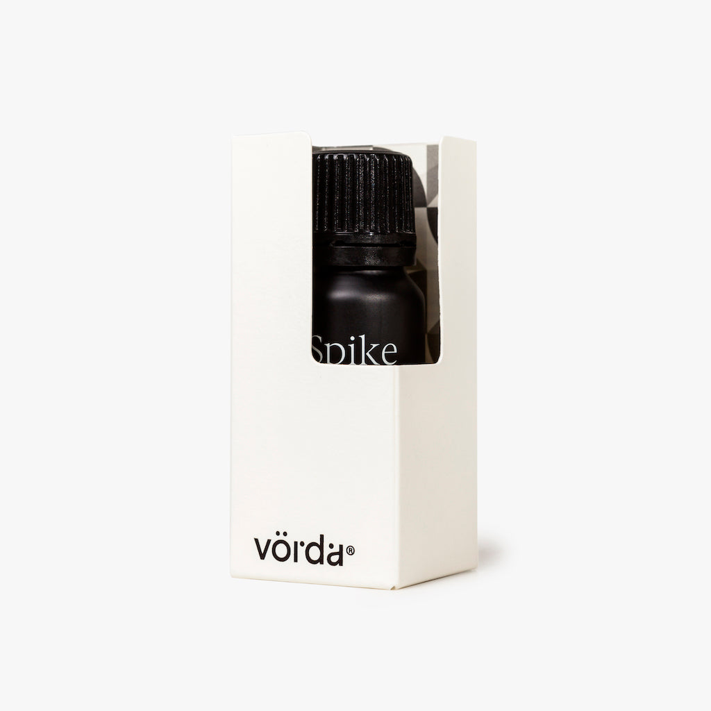 A small black bottle with a ribbed cap, partially visible inside a white rectangular box. The bottle has the word 'Spike' printed on it, and the box shows the brand name 'vörda' near the bottom.