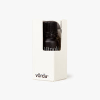 A small black bottle with a ribbed cap inside a white rectangular box, shown on a clean white background. The box has the brand name 'vörda' printed near the bottom and a window reveals part of the bottle, which shows the word 'Hinoki'.