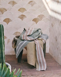 Tiled wall with patterned towels draped over a stool