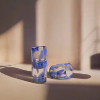Stacked drinking glasses with blue pattern on a light surface.