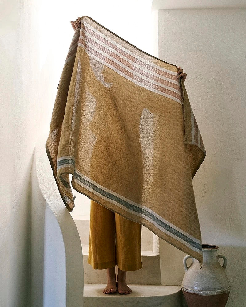 Person holding a yellow towel with stripes on a staircase