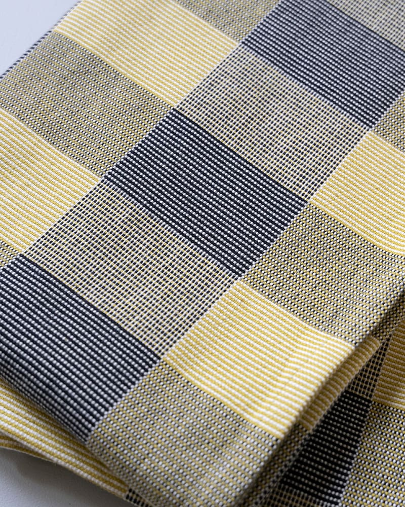 Close-up of a picnic blanket with a checkered pattern in yellow and blue.
