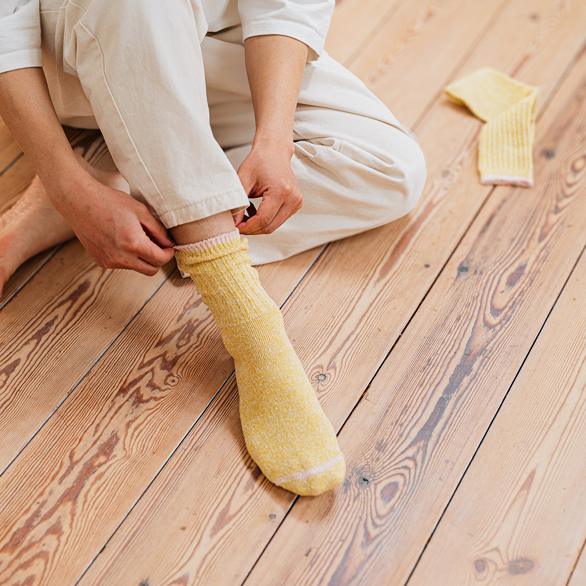 Person putting on yellow socks on a wooden floor