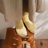 feet on a wooden stool with yellow socks and a beige skirt