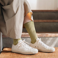 Side view of person's legs in front of a staircase wearing loose pants, chartreuse socks, and white sneakers