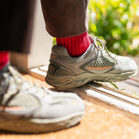 closeup of person's feet in a doorway wearing red socks and grey sneakers
