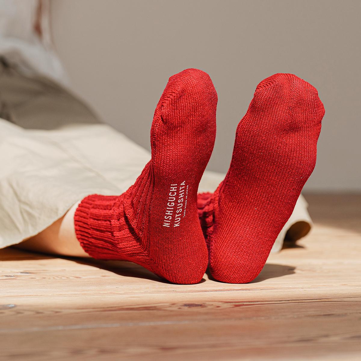 person wearing red socks with visible logo sitting on the floor
