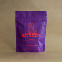 purple bag of Hinoki Bath Salt with pink text on a Kraft paper background