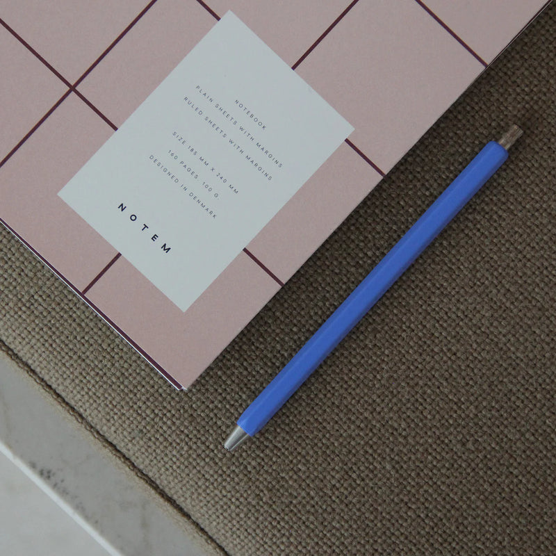 Pink notebook with a white label and blue pen on a textured surface