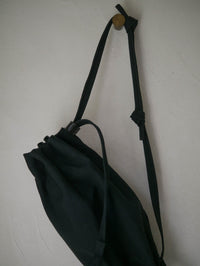 Black drawstring bag with a strap on a white background
