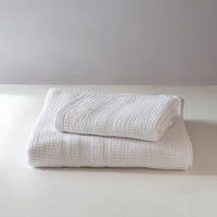 Stack of white textured towels on a light surface