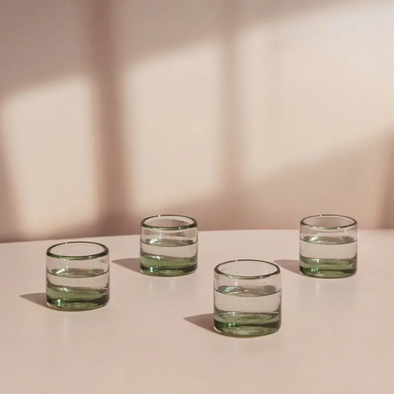 Four clear glass tumblers on a neutral surface with a soft background