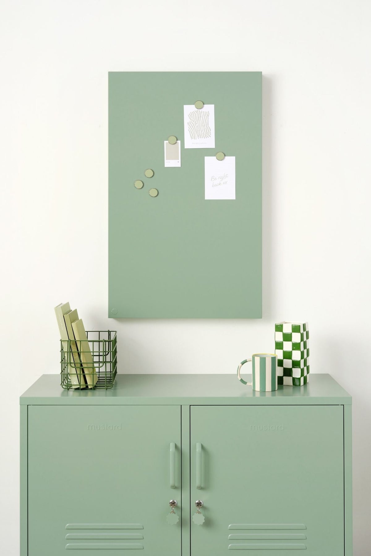 Green locker cabinet with a green magnetic display board on a white wall