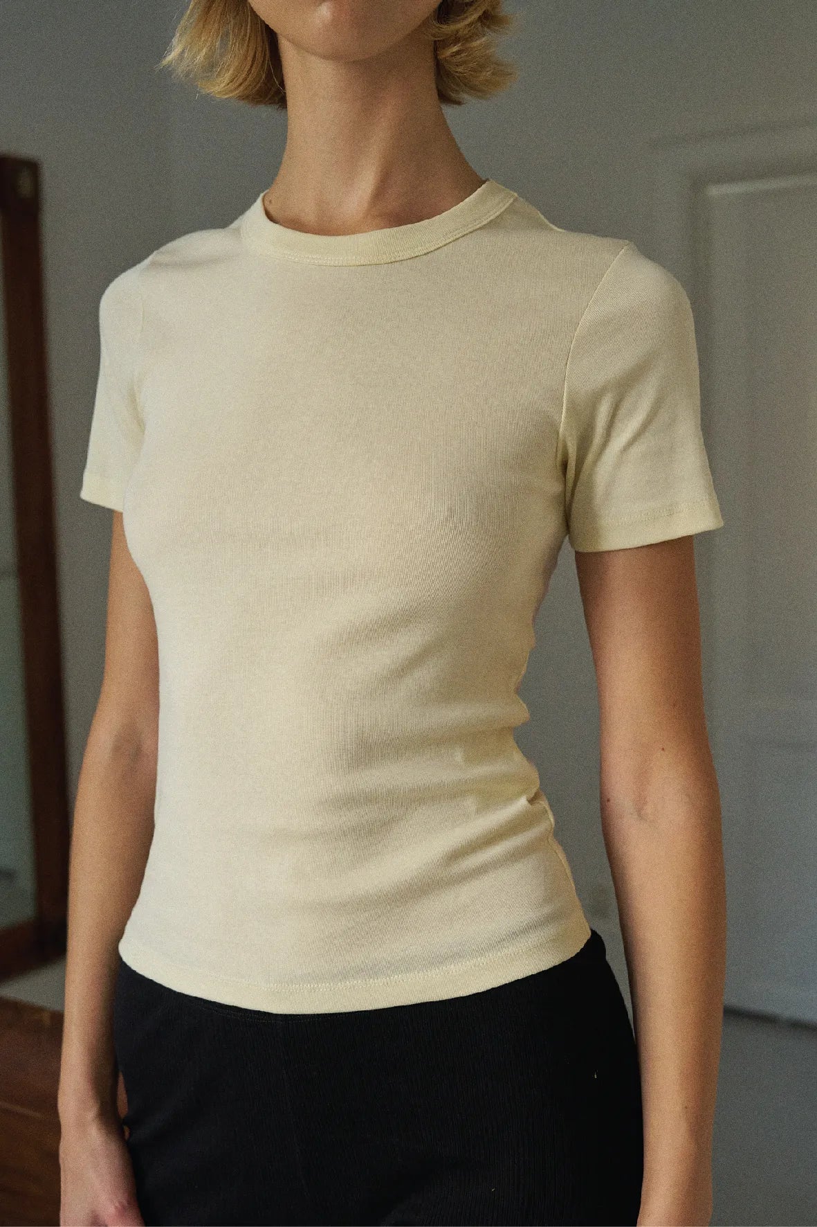 Person wearing a beige short-sleeve shirt against a neutral background