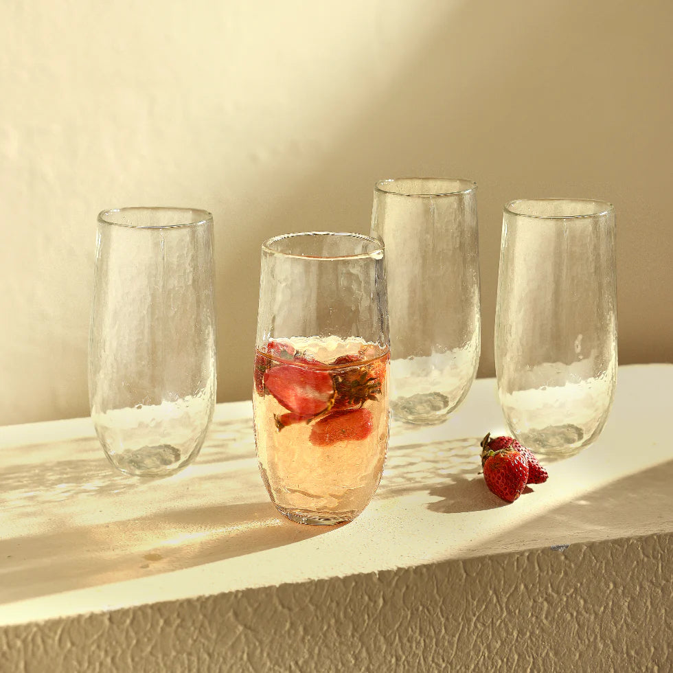 Set of 4 large pebbled drinking glasses with fruit water on a natural surface